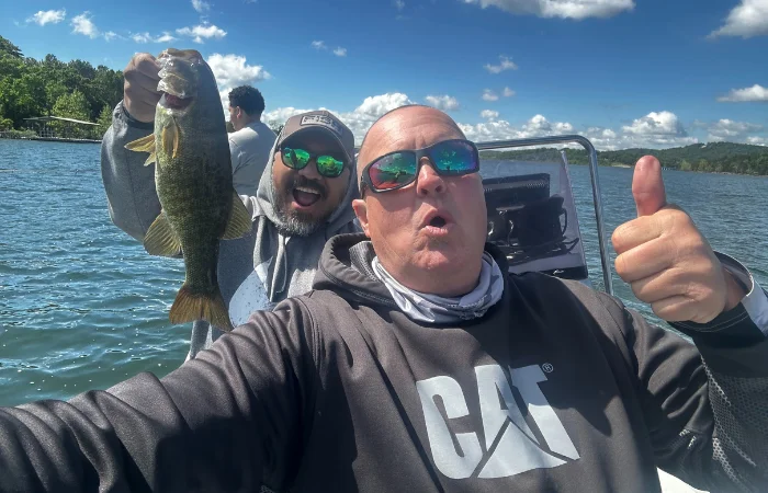 Mike Boyles with a guest holding a fish on a boat at Lake Taneycomo