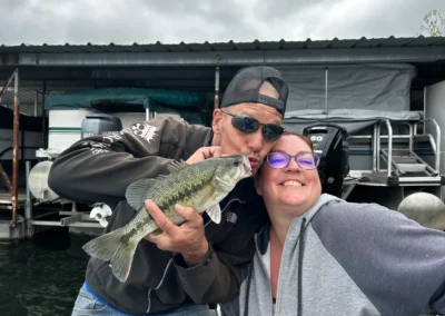 A couple smiling with a bass caught on a guided fishing trip