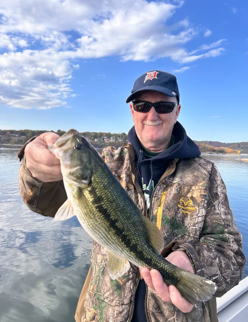 An angler holding a bass over calm water