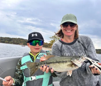 An adult and child holding a bass during a family fishing outing