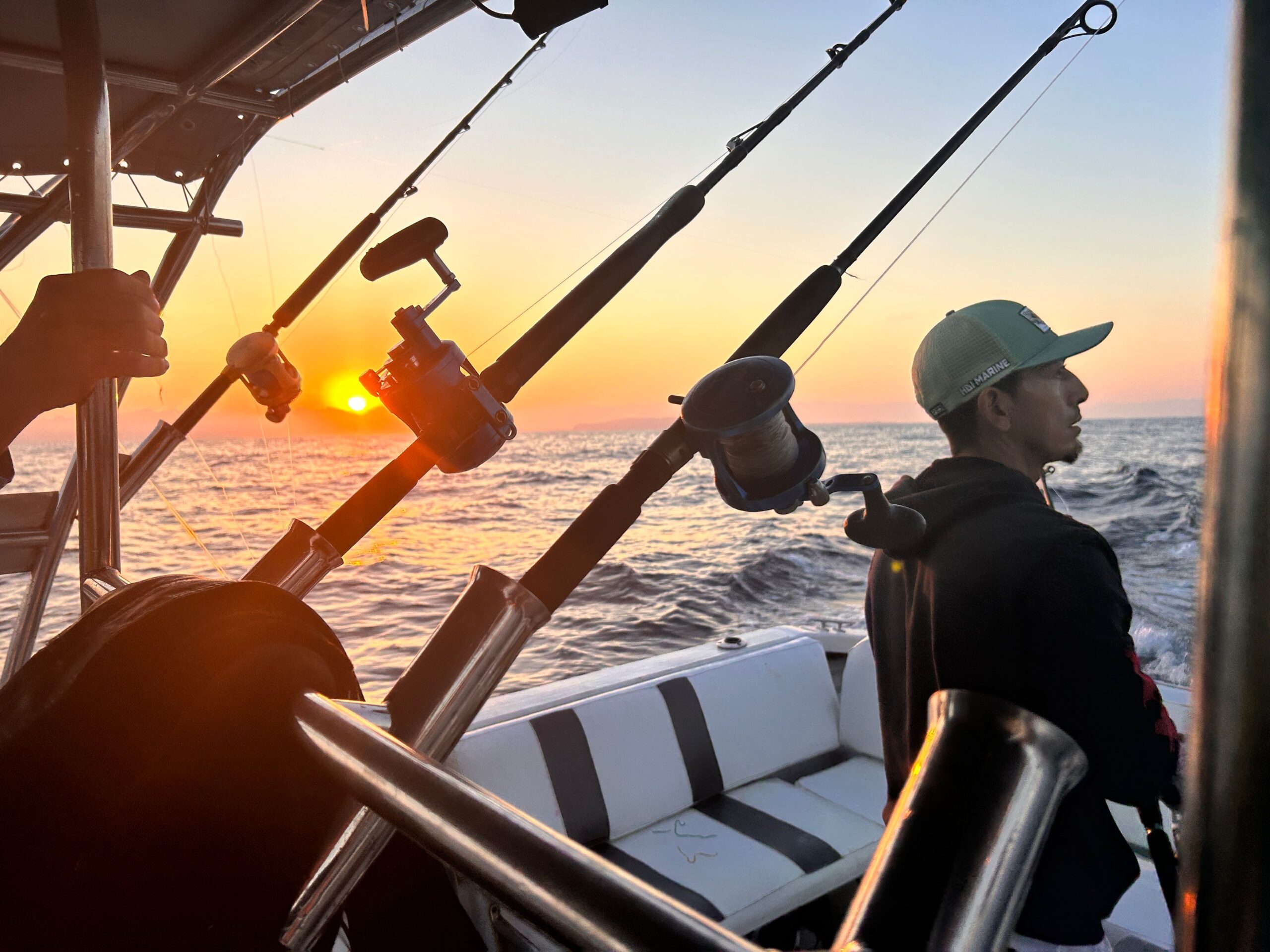 Fishing rods set up on a boat during an offshore sunset